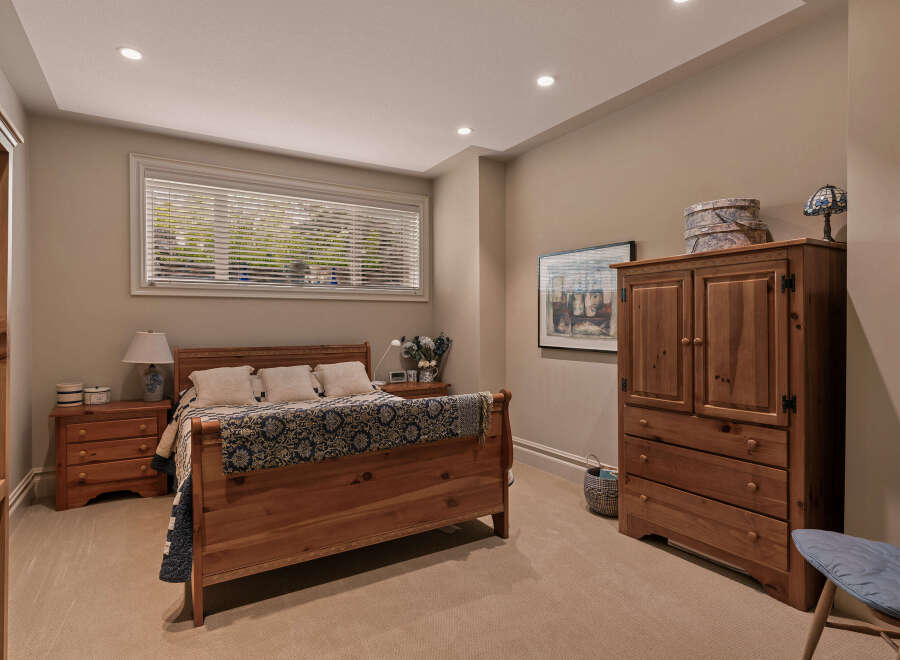 This charming bedroom features a warm wooden sleigh bed adorned with a navy and gold patterned quilt, complemented by matching nightstands.