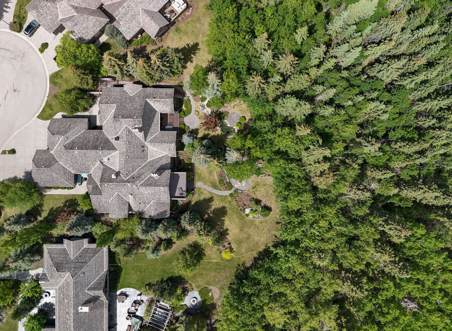 Experience luxury living in this stunning aerial view of a multi-level home featuring a distinctive grey shingle roof and expansive outdoor living spaces.