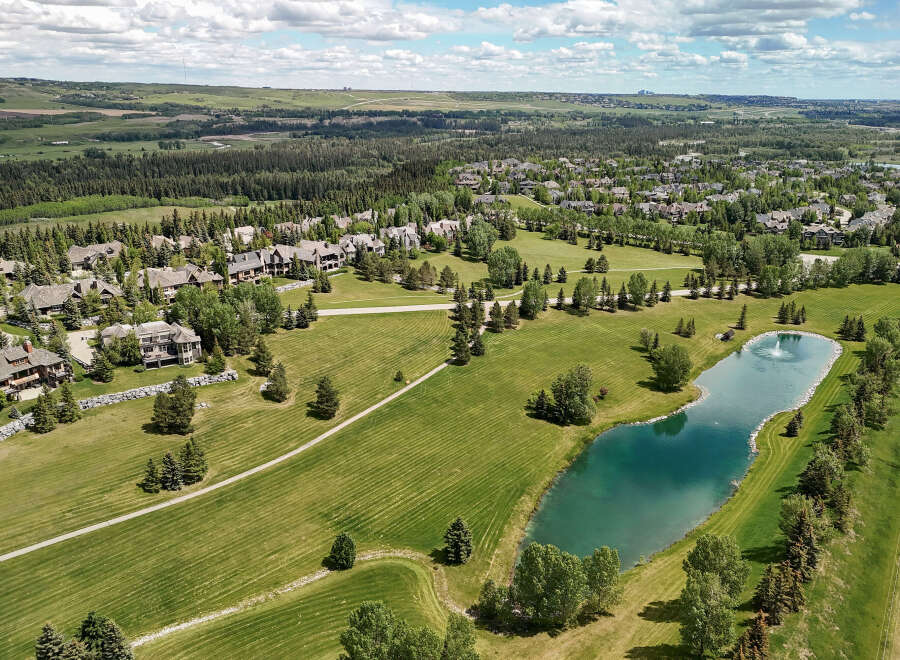 Discover luxury living in this stunning aerial view of a sprawling estate, featuring magnificent homes nestled amongst mature trees and manicured lawns.