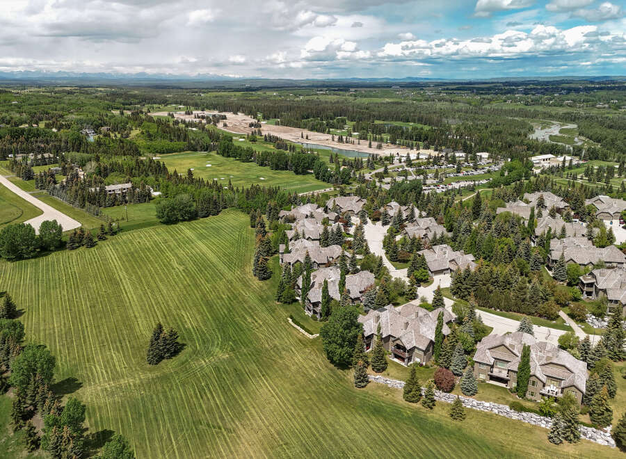 Experience luxury living in this stunning aerial view of a residential community nestled amongst mature trees and rolling green hills.