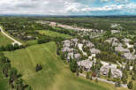 Experience luxury living in this stunning aerial view of a residential community nestled amongst mature trees and rolling green hills.