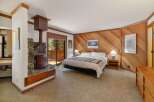 Experience cozy mountain living in this charming bedroom, featuring a striking stone fireplace with a rustic wood stove.
