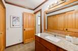 This bathroom features a spacious vanity with a granite countertop and a white undermount sink, complemented by a large mirror reflecting the wooden closet doors.