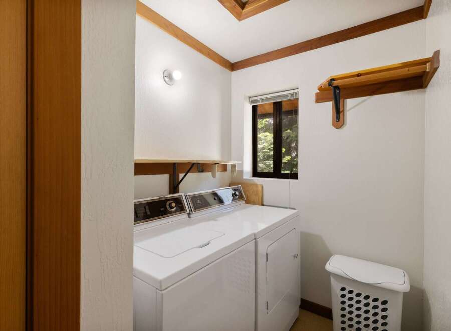 This laundry room features a white top-load washer and dryer set, perfect for handling your household chores.
