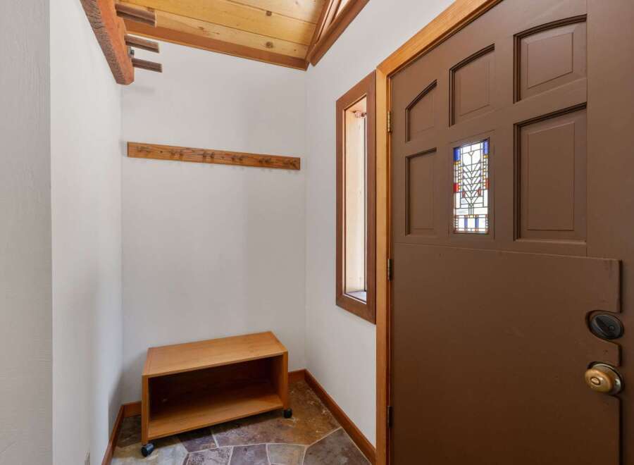 Step into this charming entryway featuring a wooden coat rack and a convenient bench for seating.