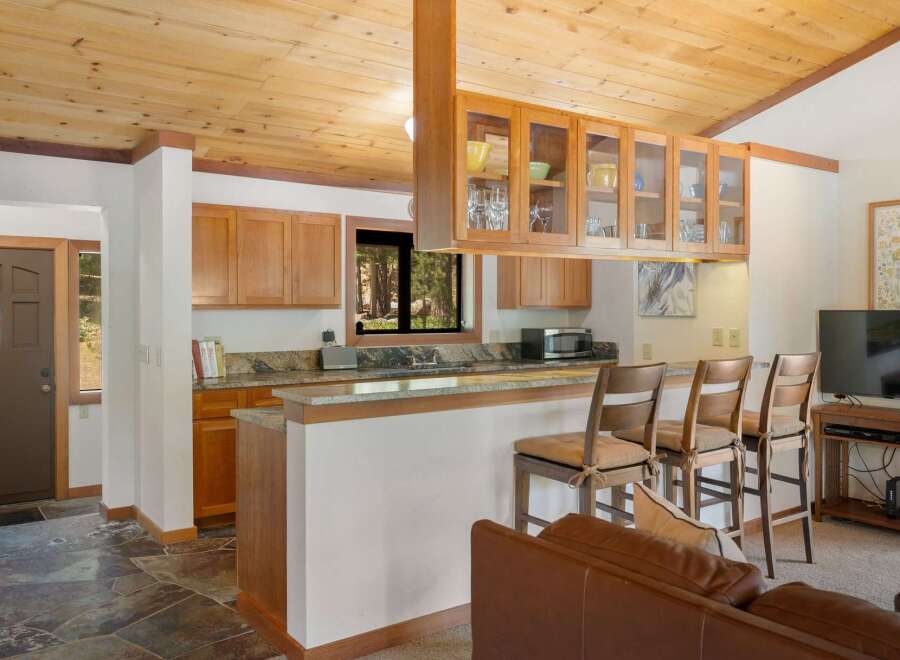 This charming kitchen and living area features a rustic wooden ceiling and ample natural light.