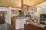 This charming kitchen and living area features a rustic wooden ceiling and ample natural light.