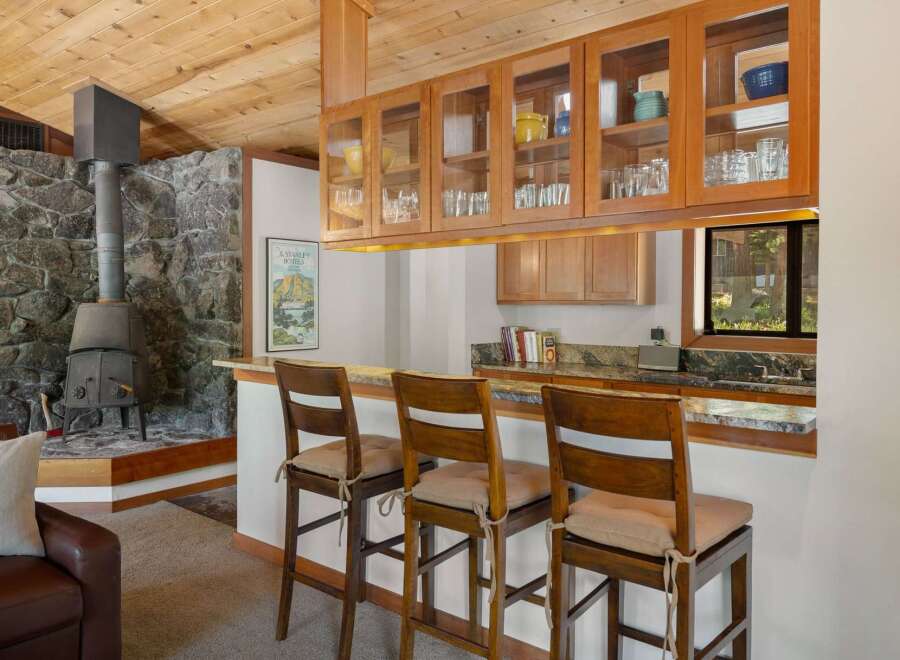 This charming kitchen features a rustic stone fireplace and a cozy breakfast bar with wooden stools.