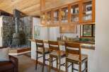 This charming kitchen features a rustic stone fireplace and a cozy breakfast bar with wooden stools.