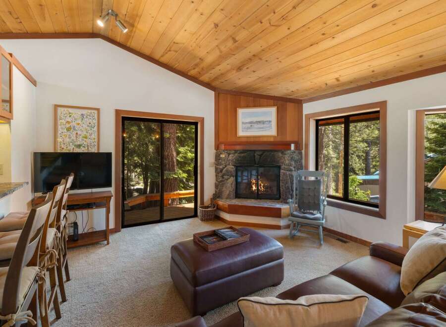 Cozy living room featuring a stone fireplace and a large leather ottoman, perfect for relaxing evenings.
