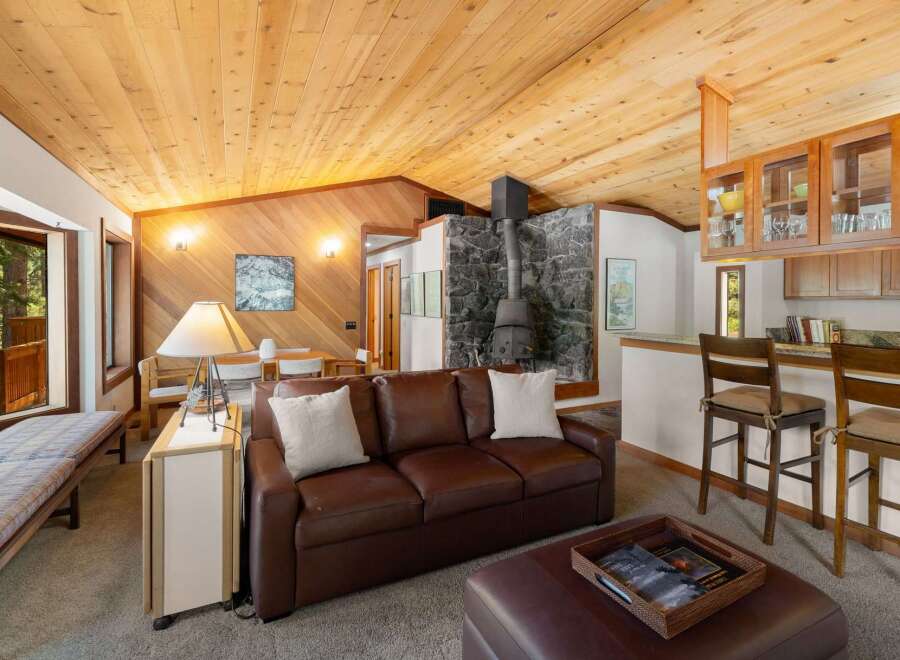 Experience cozy living in this charming mountain retreat, featuring a striking stone fireplace and a warm, wood-paneled interior.