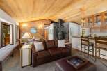Experience cozy living in this charming mountain retreat, featuring a striking stone fireplace and a warm, wood-paneled interior.