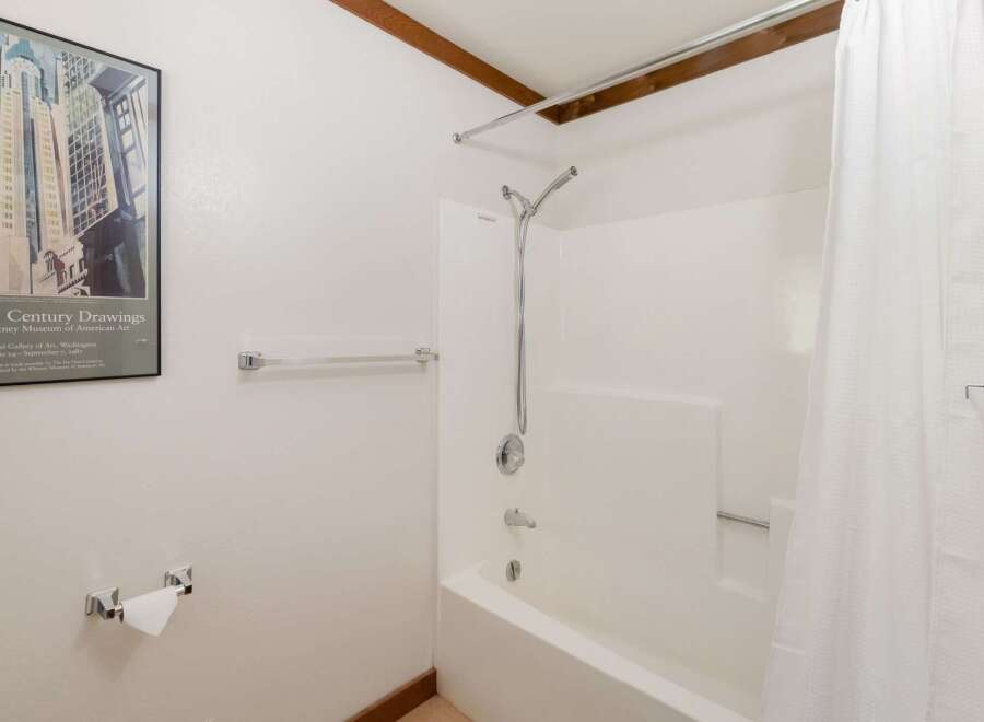 This bathroom features a clean and functional design with a white bathtub and shower combination.