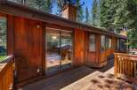 Experience rustic charm in this wooden cabin, featuring a spacious deck perfect for outdoor living and surrounded by lush pine trees.