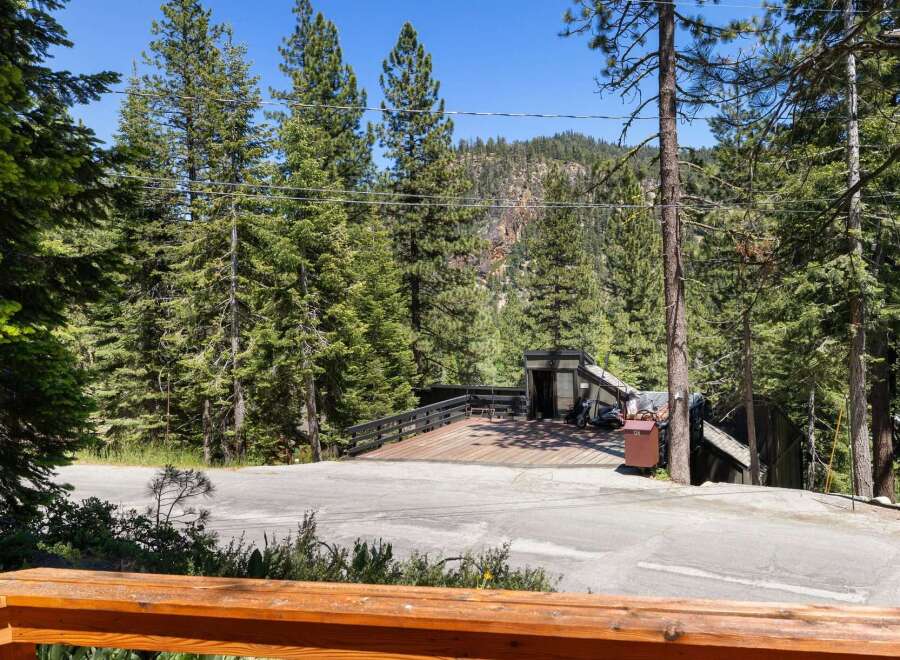 Experience mountain living with this unique property featuring a spacious wooden deck perfect for outdoor entertaining and enjoying the surrounding forest views.