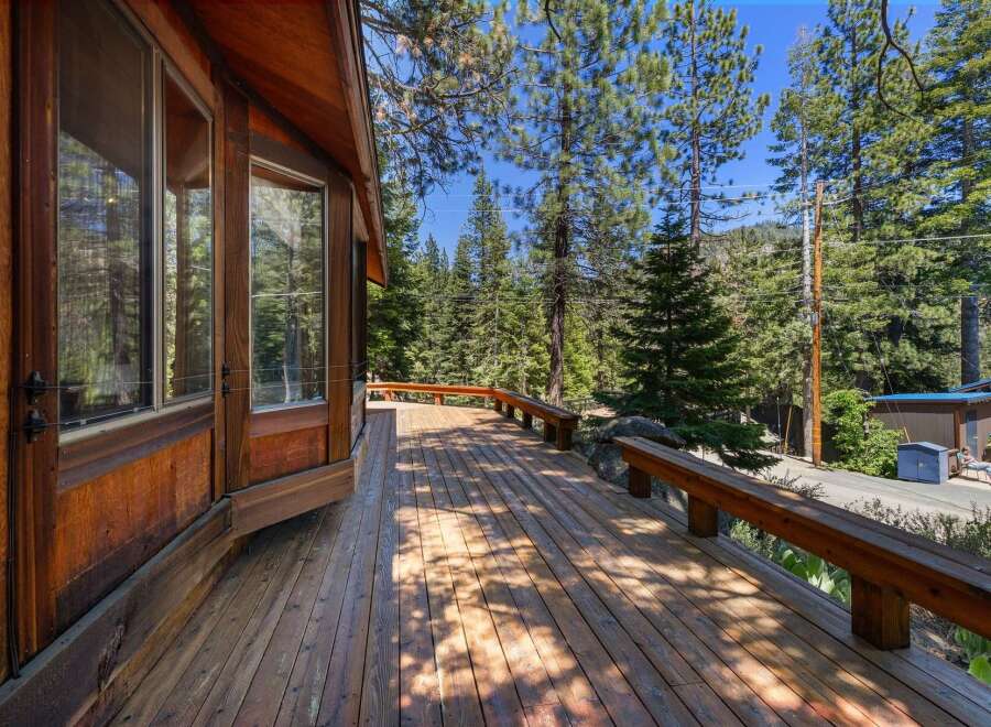 Enjoy the serene mountain lifestyle from this charming cabin's expansive wooden deck, perfect for outdoor relaxation and entertaining.