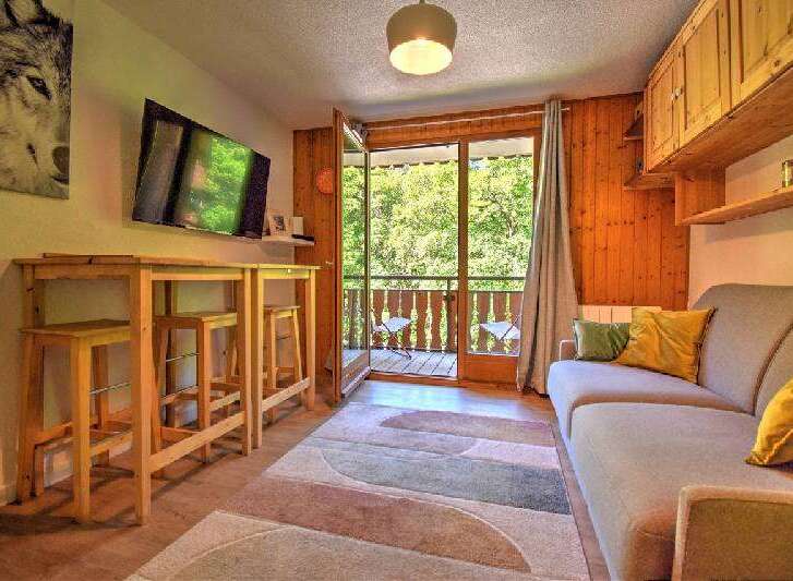 Enjoy a cozy mountain retreat in this charming living area, featuring a modern TV, a stylish high-top table with stools, and a comfortable sofa perfect for relaxing.