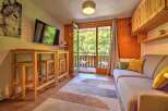 Enjoy a cozy mountain retreat in this charming living area, featuring a modern TV, a stylish high-top table with stools, and a comfortable sofa perfect for relaxing.