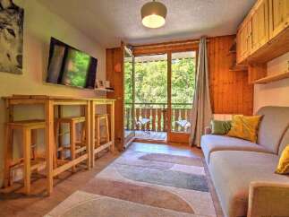 Enjoy a cozy mountain retreat in this charming living area, featuring a modern TV, a stylish high-top table with stools, and a comfortable sofa perfect for relaxing.