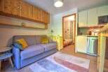 This cozy studio apartment features a comfortable sofa, a compact kitchen with a dishwasher, and a separate sleeping area.