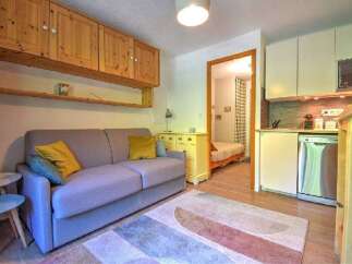 This cozy studio apartment features a comfortable sofa, a compact kitchen with a dishwasher, and a separate sleeping area.