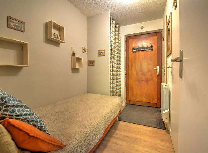 Discover this cozy studio apartment featuring a comfortable single bed adorned with decorative pillows, perfect for relaxation.