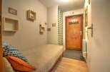 Discover this cozy studio apartment featuring a comfortable single bed adorned with decorative pillows, perfect for relaxation.