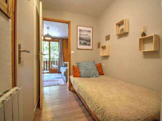 Discover this charming room featuring a cozy single bed adorned with decorative pillows and a plush throw.