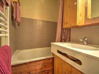 This charming bathroom features a bathtub with tiled walls and a wooden base, perfect for a relaxing soak.
