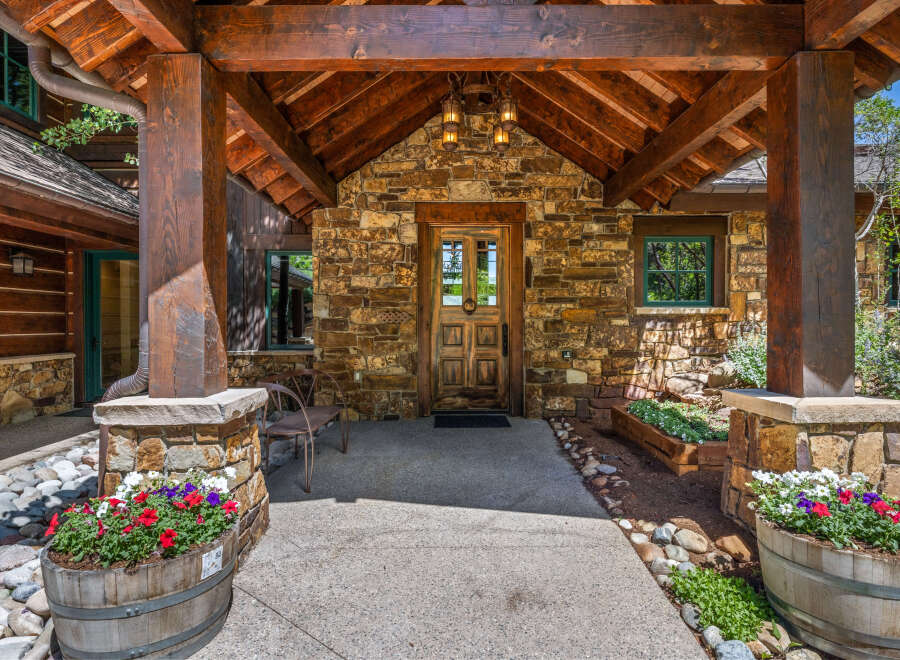 Experience rustic charm with this inviting entryway, featuring a sturdy wooden door set against a natural stone facade.