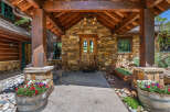 Experience rustic charm with this inviting entryway, featuring a sturdy wooden door set against a natural stone facade.
