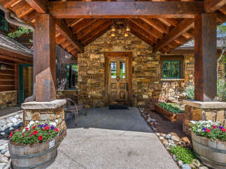 Experience rustic charm with this inviting entryway, featuring a sturdy wooden door set against a natural stone facade.