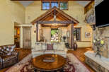 Experience rustic luxury in this stunning living room, featuring a grand stone fireplace and a soaring wooden-beamed ceiling.