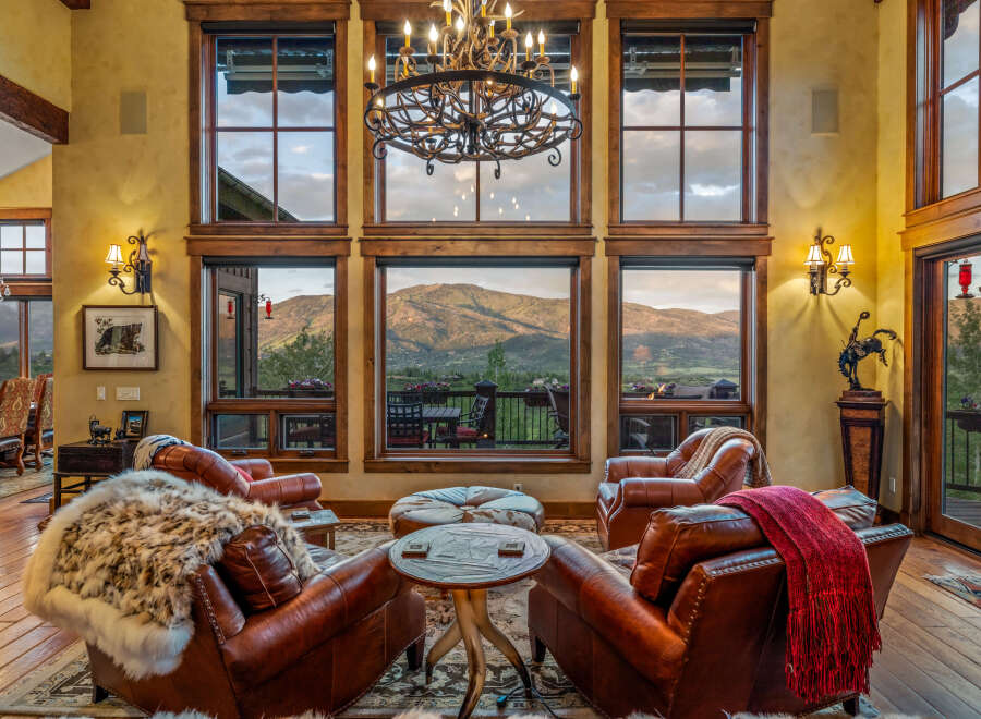 Experience luxury mountain living in this stunning great room, featuring plush leather armchairs and a cozy fur throw perfect for relaxing evenings.