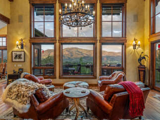 Experience luxury mountain living in this stunning great room, featuring plush leather armchairs and a cozy fur throw perfect for relaxing evenings.