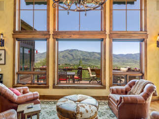 Experience breathtaking mountain views from this stunning living room, featuring expansive windows that flood the space with natural light.