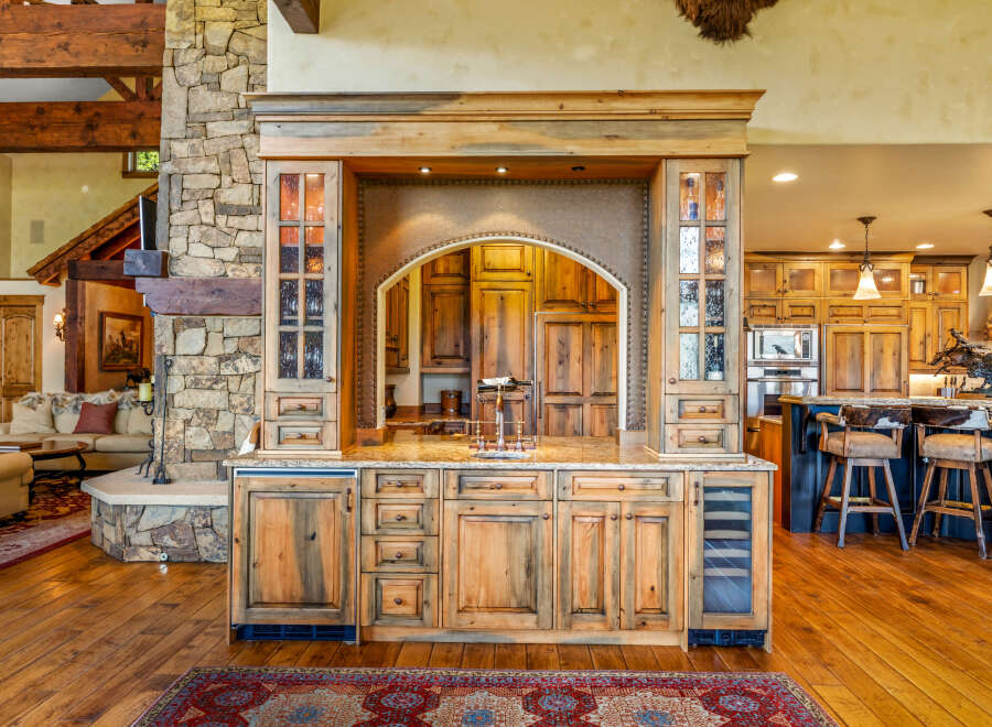 Experience rustic luxury with this stunning custom-built bar area, featuring rich wood cabinetry, a stone accent wall, and a granite countertop.