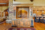 Experience rustic luxury with this stunning custom-built bar area, featuring rich wood cabinetry, a stone accent wall, and a granite countertop.