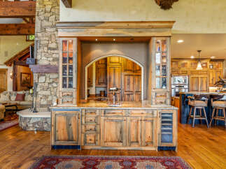 Experience rustic luxury with this stunning custom-built bar area, featuring rich wood cabinetry, a stone accent wall, and a granite countertop.