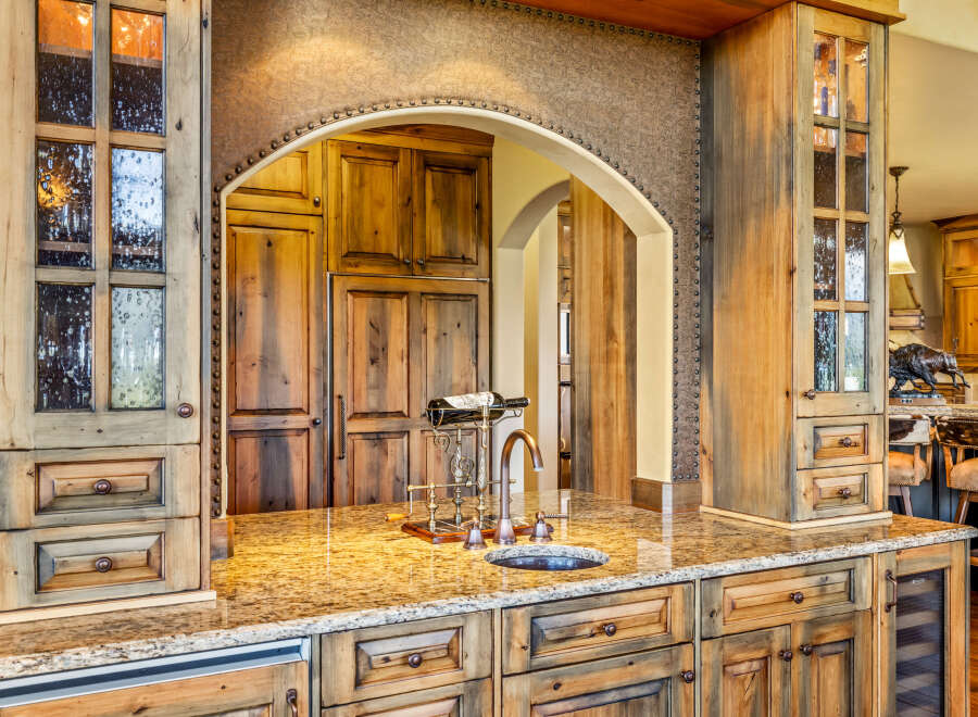 Experience luxury in this stunning kitchen featuring custom knotty alder cabinetry with decorative glass doors and a granite countertop.