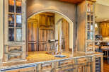 Experience luxury in this stunning kitchen featuring custom knotty alder cabinetry with decorative glass doors and a granite countertop.