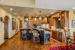 Experience rustic elegance in this stunning kitchen, featuring custom wood cabinetry, a granite-topped island with bar seating, and a striking copper range hood.