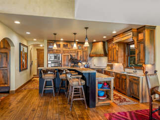 Experience rustic elegance in this stunning kitchen, featuring custom wood cabinetry, a granite-topped island with bar seating, and a striking copper range hood.