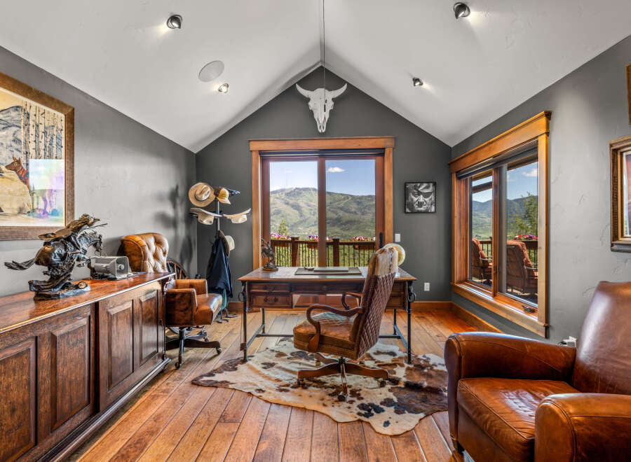 Experience rustic elegance in this executive office, featuring a grand wooden desk and plush leather chairs.