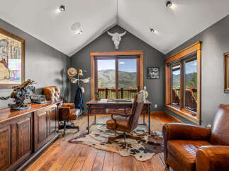 Experience rustic elegance in this executive office, featuring a grand wooden desk and plush leather chairs.