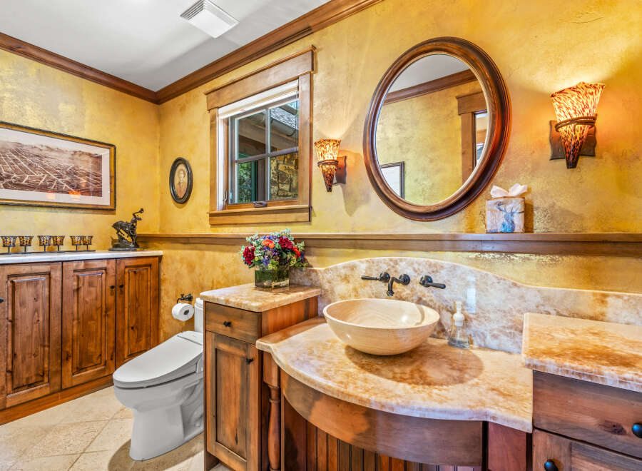 This luxurious bathroom features a stunning golden textured wall, complemented by warm wood cabinetry and a beautiful marble countertop.