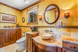 This luxurious bathroom features a stunning golden textured wall, complemented by warm wood cabinetry and a beautiful marble countertop.