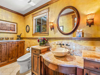 This luxurious bathroom features a stunning golden textured wall, complemented by warm wood cabinetry and a beautiful marble countertop.