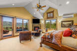 Experience luxury mountain living in this stunning bedroom featuring a cozy stone fireplace and breathtaking views from the private balcony.