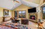 Experience luxury mountain living in this stunning bedroom featuring a cozy stone fireplace and breathtaking panoramic views from the large windows.
